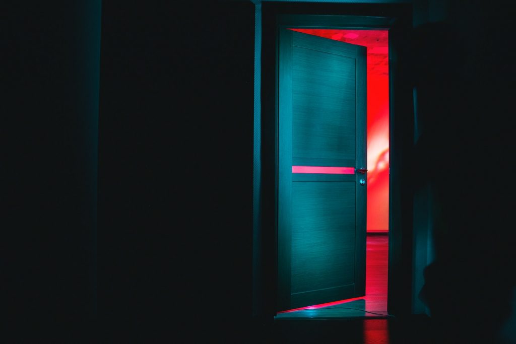 Puerta blanca de madera en la oscuridad con una luz roja de fondo