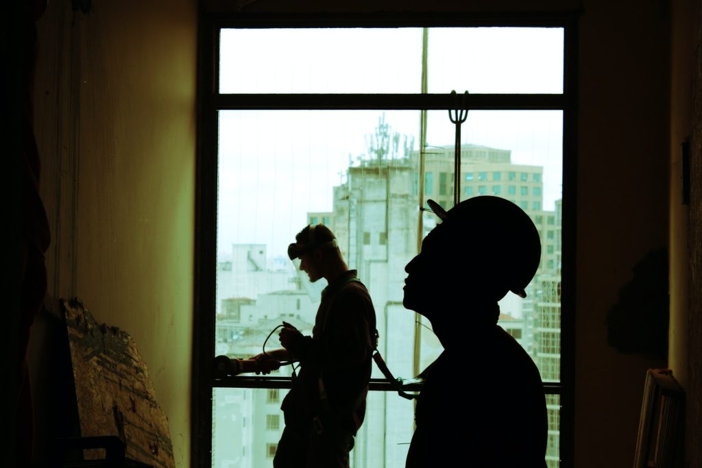 Dos hombres con casco dentro de obra de construcción al lado de la ventana