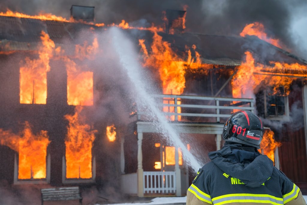 Bombero apagando fuego de una casa